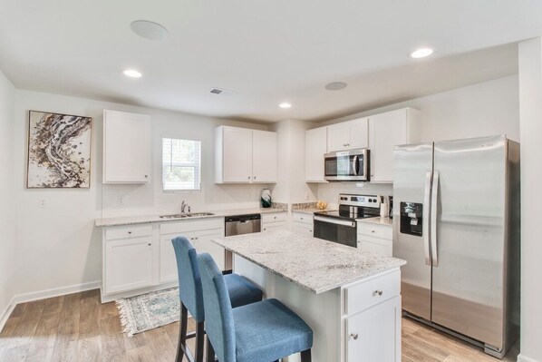 A modern kitchen with white cabinets, stainless steel appliances, and a granite countertop.