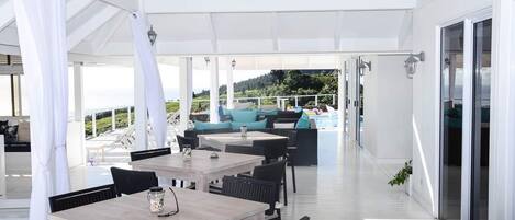 An outdoor patio with tables and chairs, a pool area, and a view of the landscape.