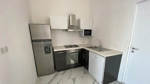 Una cocina compacta equipada con refrigerador, estufa, microondas, pileta y lavavajillas.