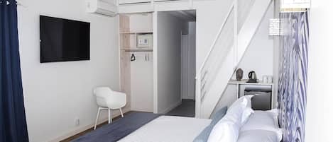 A modern hotel room with a bed, a desk, a chair, and a staircase leading to an upper level.