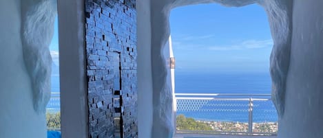 A modern bathroom with a bathtub, a shower, and a view of the sea.