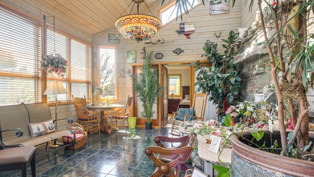 A cozy interior with a wooden ceiling, a hanging floral chandelier, a dining area with a table and chairs, and a large potted plant. - Unique Home w/ Beautiful Mtn Views! (Sequim)