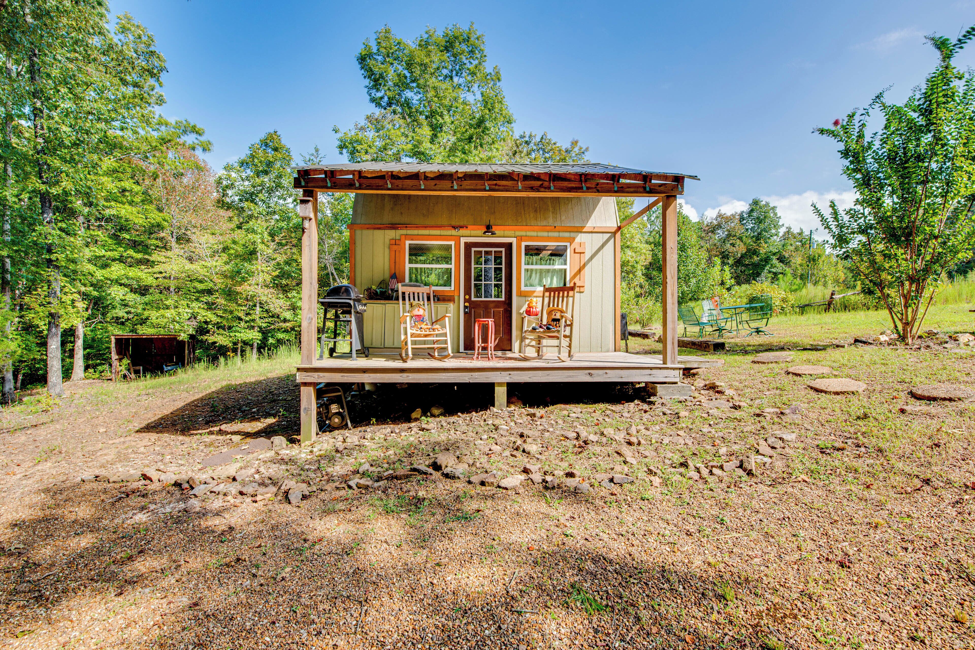 A rustic cabin with a porch, a front door, and a small deck area.