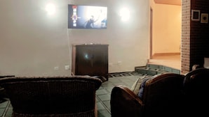 A living room with a television mounted on the wall, a small cabinet, and a staircase leading to an upper level. - Beach House Unid. 3 Casas Praia Guarujá (Guarujá)
