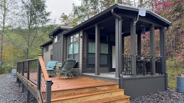 Een huis met een overdekte veranda, houten trappen en twee stoelen.