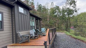 Een chalet met een houten terras, zitplaatsen buiten en uitzicht op het omliggende bos.