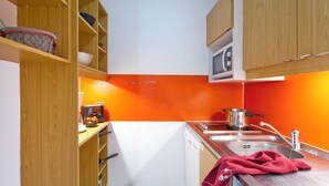 A compact kitchen with wooden cabinets, a microwave, a toaster, and a sink.