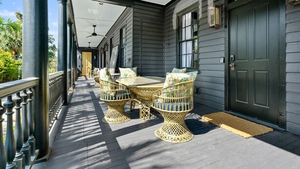 Een overdekt terras met een tafel, stoelen, een deur en een raam.