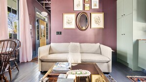 Un salon avec un canapé, une table basse et des œuvres d’art encadrées accrochées au mur.
