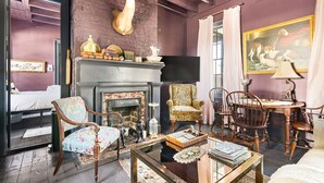 Une pièce avec une cheminée, un lit, une table à manger avec des chaises et une tête de cerf accrochée au mur.