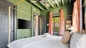 Une chambre dotée d’un grand lit, d’un téléviseur à écran plat et d’une fenêtre avec des rideaux.