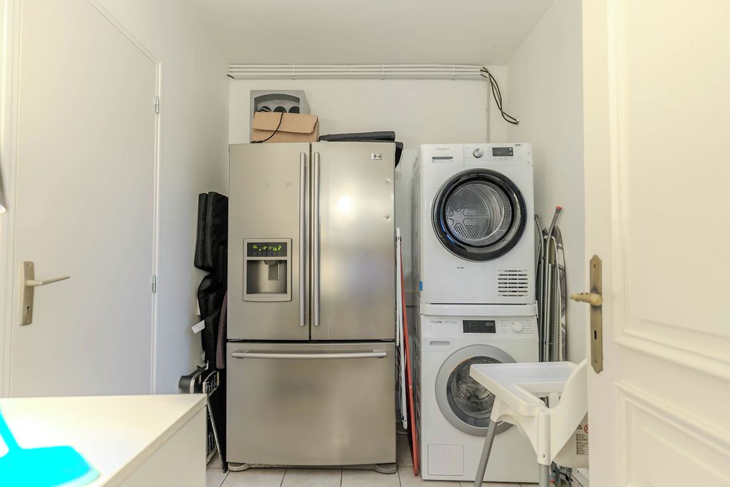 Een praktische keuken met een koelkast van roestvrij staal, een ingebouwde wasmachine en een klein aanrecht.