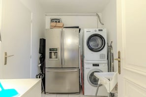 A compact kitchen with a stainless steel refrigerator, a built-in washing machine, and a small countertop.