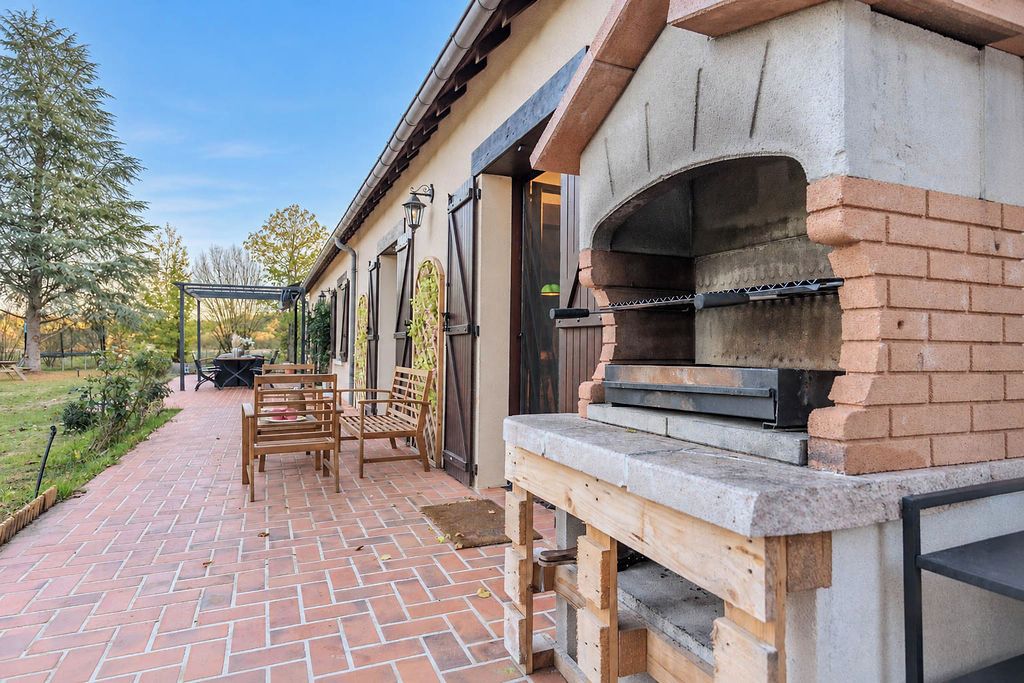 Eine Terrasse im Freien mit rotem Ziegelboden, Holzmöbeln und einem Backofen aus Ziegeln.