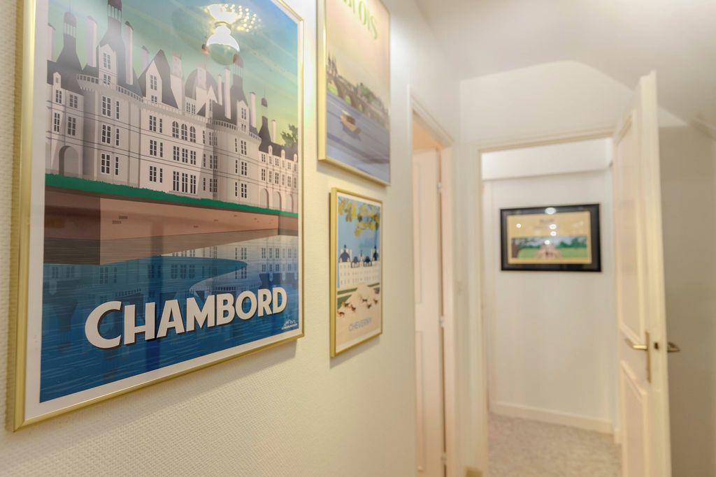Un pasillo con obras enmarcadas en las paredes, incluyendo un cartel llamativo de 'CHAMBORD'.