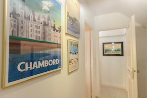 A hallway with framed artwork on the walls, including a prominent 'CHAMBORD' sign.