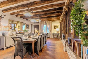 A dining area with a wooden ceiling, a long table with chairs, and a view of the outdoors. - Chambord - Beautiful estate (12 people) with a private park and pool (Thoury)