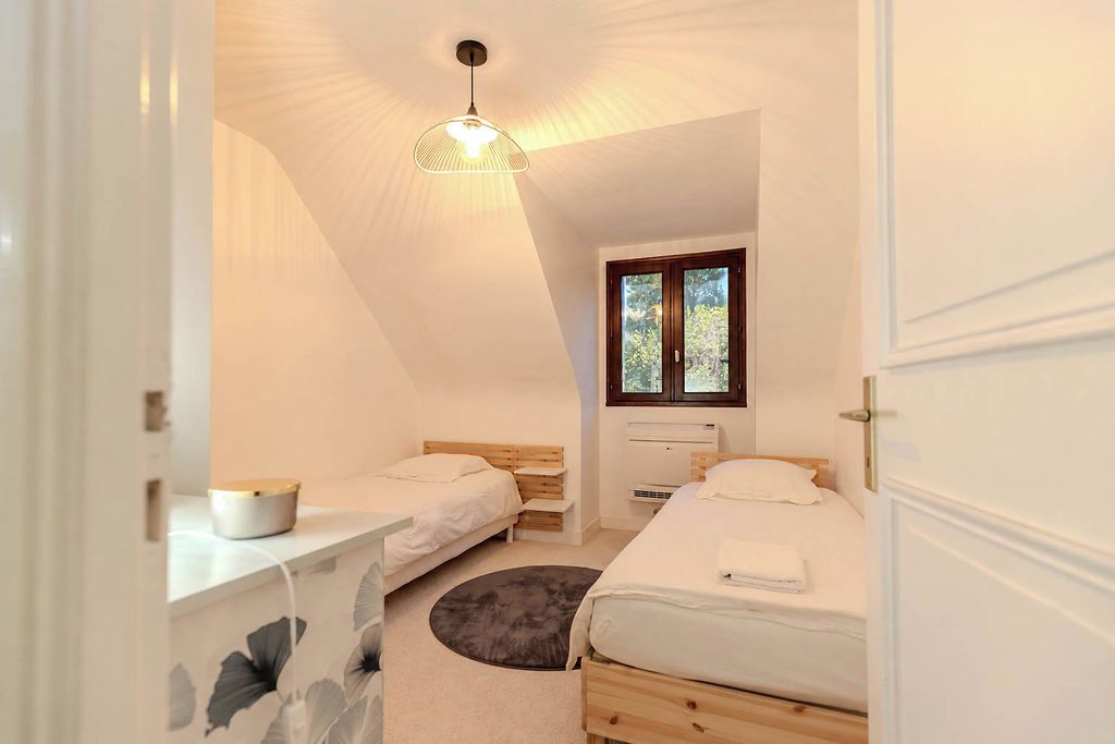 Un dormitorio con dos camas, una ventana, un radiador y un escritorio con una lámpara.