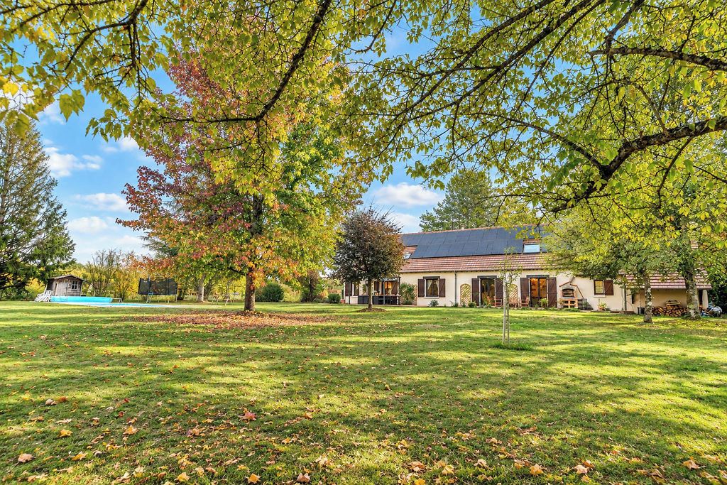 Een huis met een gazon, bomen en een heldere lucht.