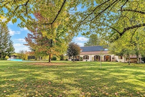 A house with a lawn, trees, and a clear sky.