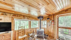 L’intérieur d’un chalet en bois, avec une grande cheminée, un téléviseur et un coin salon confortable.