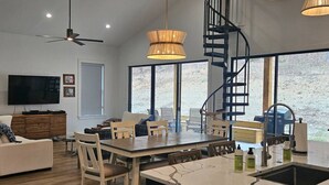 Une cuisine moderne dotée d’un plan de travail en marbre, d’un évier encastré et d’un coin repas avec des chaises et une table en bois.