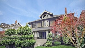 Une maison à deux étages avec un porche à l’avant, une cheminée et une pelouse bien entretenue.