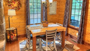 A wooden dining room with a table, chairs, a chandelier, and curtains. - Tranquil Escape Close to Dining & Entertainment (Millersburg)