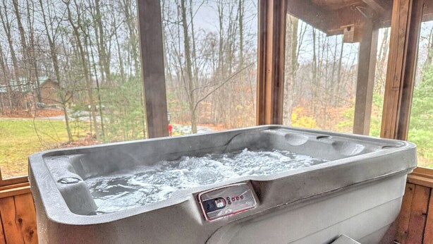 A hot tub with a control panel, set in a wooden cabin with large windows overlooking a forested area. - Tranquil Escape Close to Dining & Entertainment (Millersburg)