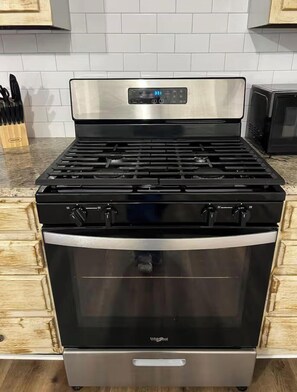 A stainless steel stove with a digital display, a stainless steel oven, and a wooden cabinet. - Hayden House
3 bedroom/2 bathroom/ 3 beds (Vernon)