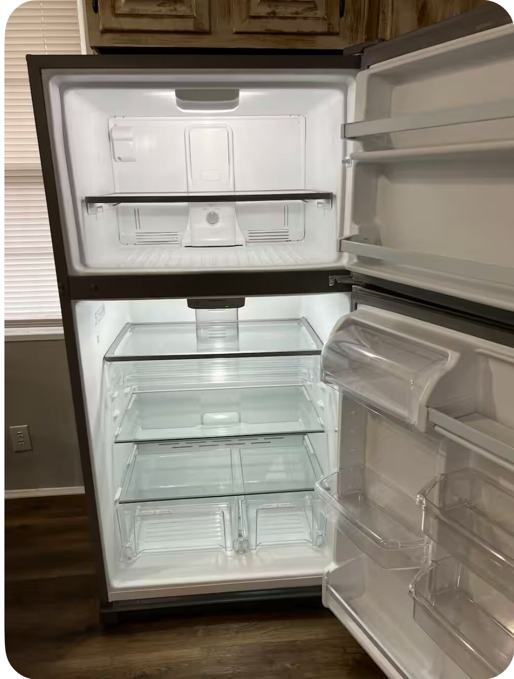 Un refrigerador abierto con varios cajones transparentes y un compartimento congelador.