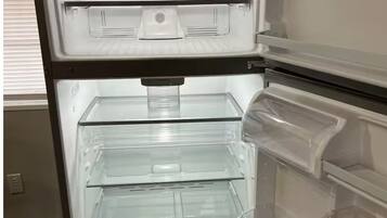 Un refrigerador abierto con varios cajones transparentes y un compartimento congelador.