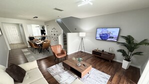 Una sala de estar moderna con un sofá, una mesa de centro y un televisor instalado en la pared.