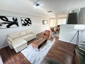 A living room with a sofa, coffee table, and a dining area with chairs and a table.