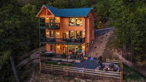 Une cabane en rondins à deux étages, dotée d’un balcon, d’une piscine et d’un espace aménagé pour faire un feu de camp.