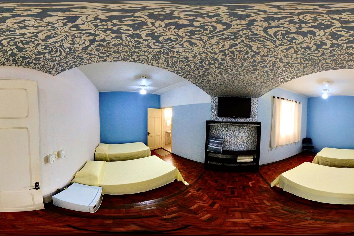 A room with two beds, a television, and a patterned ceiling.