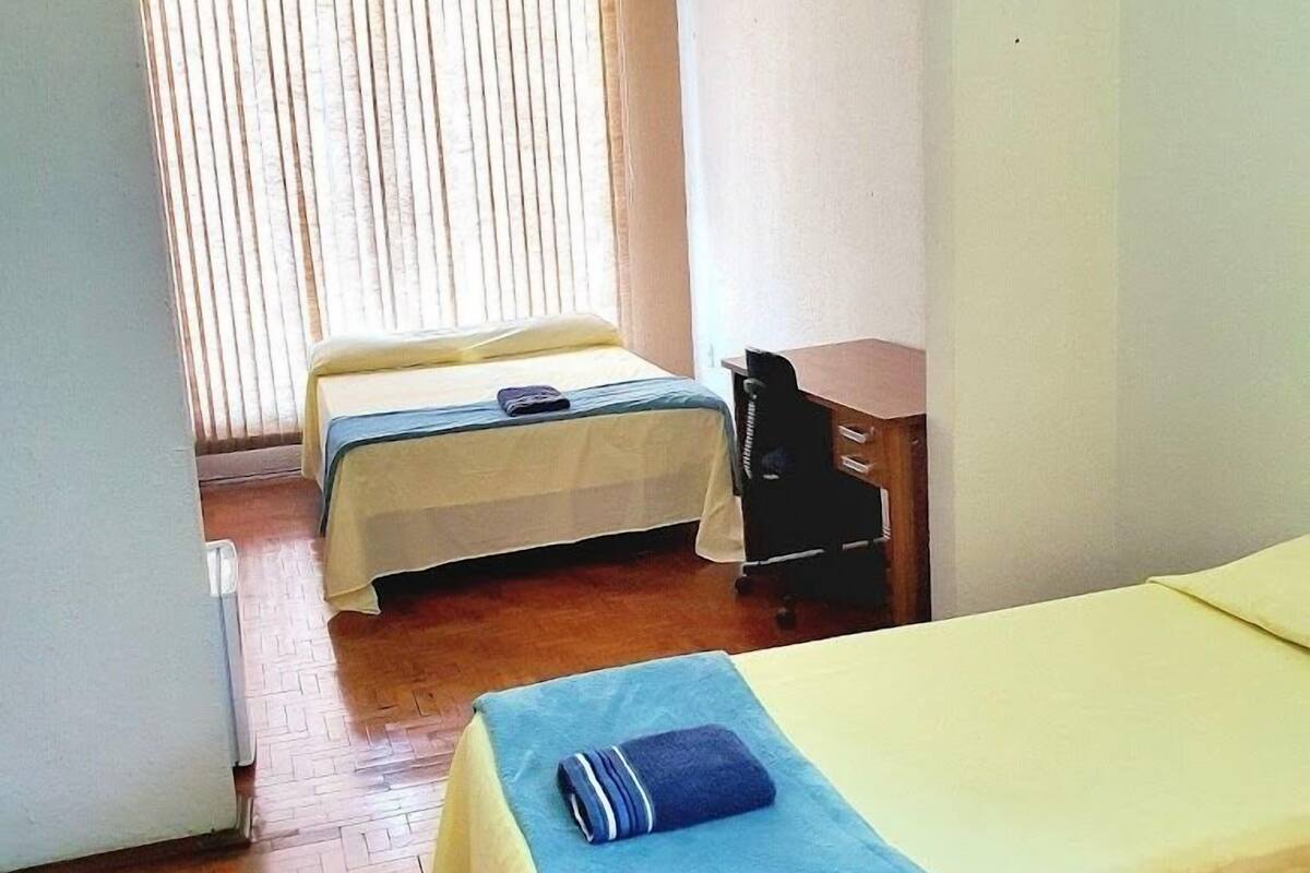 A room with two beds, a desk, and a chair.