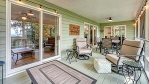 Eine überdachte Veranda mit Schiebeglastüren, Gartenmöbeln und einem Deckenventilator.