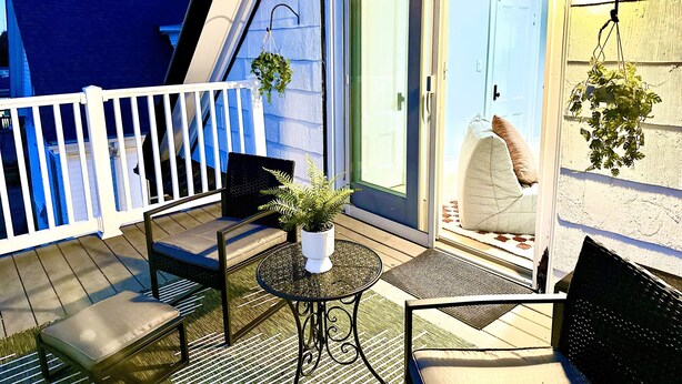 A balcony with a white railing, a small round table, two chairs, and a potted plant. - Family Retreat - Stunning 5BR-2BA with Parking/ Near Savin Hill Station (Boston)