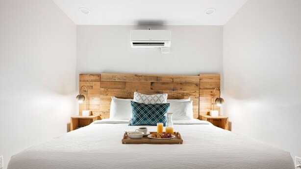 A neatly made bed with a wooden headboard, two bedside lamps, and a tray with breakfast items.