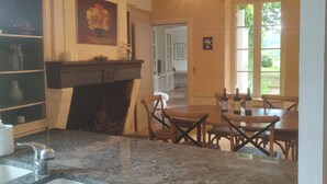 A kitchen with granite countertops, a sink, a dining area with wooden chairs, and a fireplace.