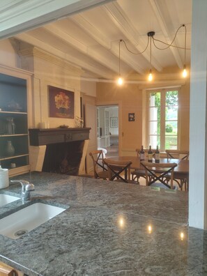 A kitchen with granite countertops, a sink, a dining area with wooden chairs, and a fireplace.