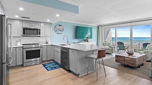 A modern kitchen with a large island, stainless steel appliances, and a view of the ocean.