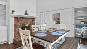 A dining area with a brick fireplace, white walls, and a white door leading to a storage room. - Near Newport, Beaches, Golf & Navy Base (Middletown)
