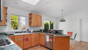 A modern kitchen with wooden cabinets, a built-in dishwasher, and a large island. - Near Newport, Beaches, Golf & Navy Base (Middletown)