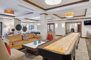 A spacious room with a pool table, comfortable seating, and a television.