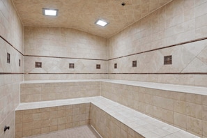 Un bagno piastrellato con doccia d'angolo, rubinetteria a vista e una lampada a soffitto.