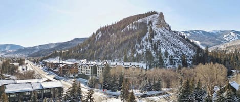 Un centro de esquí con una montaña destacada, edificios con tejados nevados y un cielo despejado.