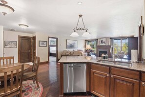 A kitchen with a central island, stainless steel dishwasher, wooden cabinets, and a dining area with a wooden table and chairs.