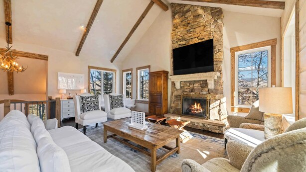 A spacious living room with a stone fireplace, white sofas, and a wooden coffee table.